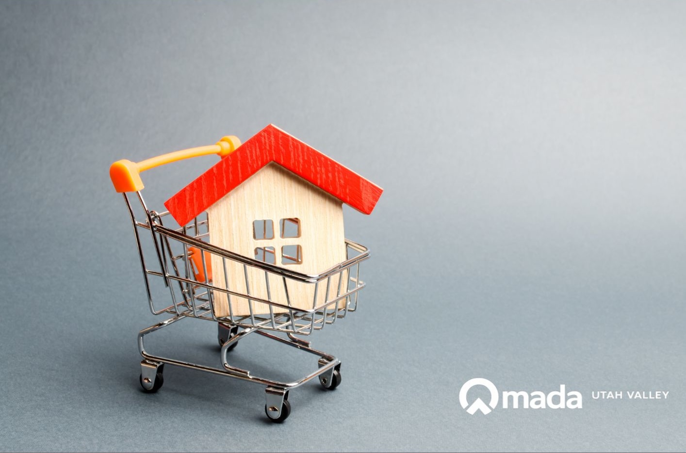 A wooden house in a shopping cart with the Omada Utah Valley logo